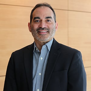  Headshot of Jorge Sanchez wearing a black suit coat and a collared shirt