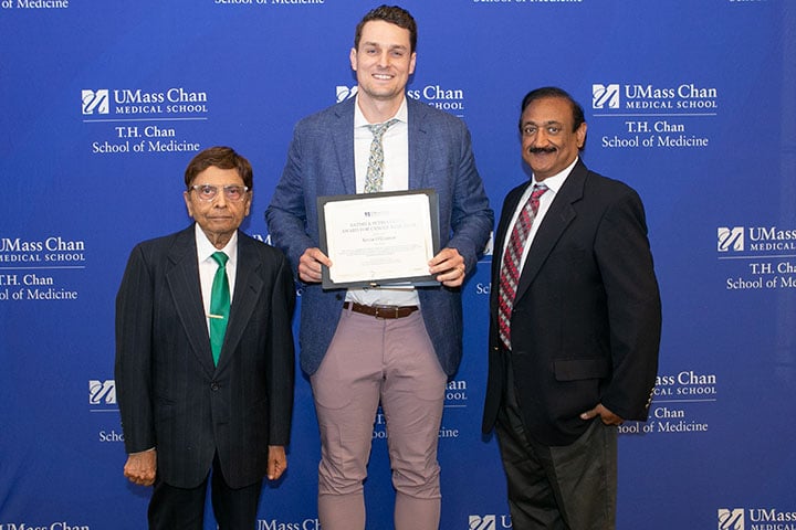Kevin O'Connor holding a plaque alongside Satish Gupta and his son, Sanjeev.