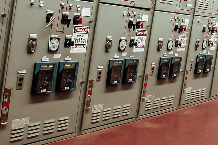 The image shows a row of switchboards located inside the power plant