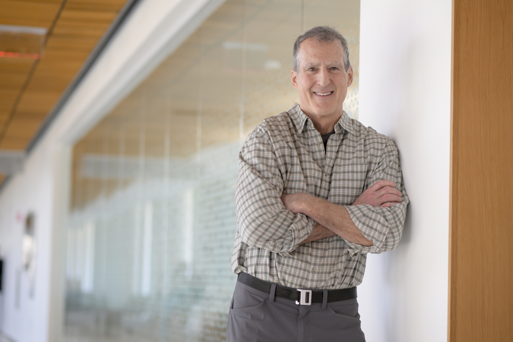 Photo of Craig Mello leaning against a wall in the Paul J. DiMare Center. 