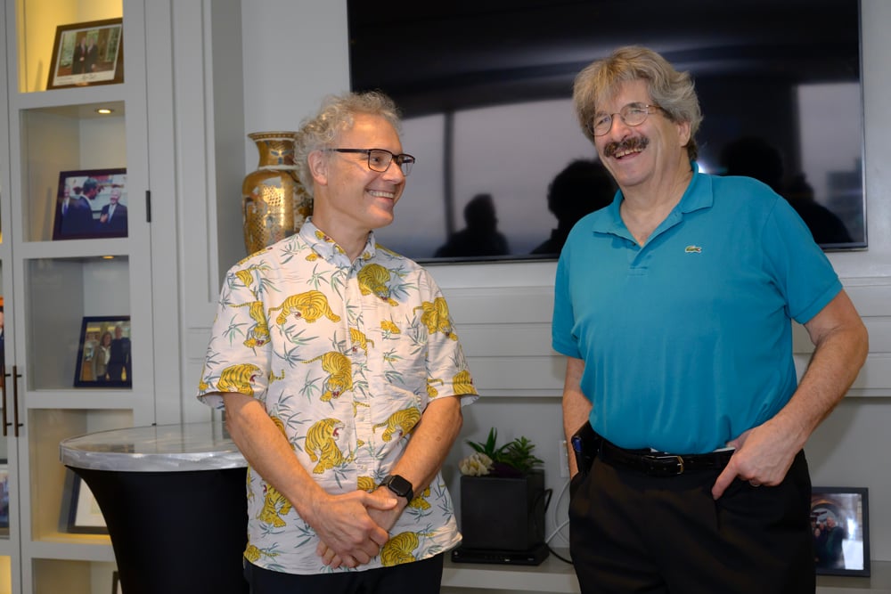 Dr. Ambros and Dr. Ruvkun standing side-by-side at the UMass Club in Boston the afternoon of the Nobel announcement. Ambros is wearing a shirt with yellow tigers. Gary wears a turquoise polo shirt. 