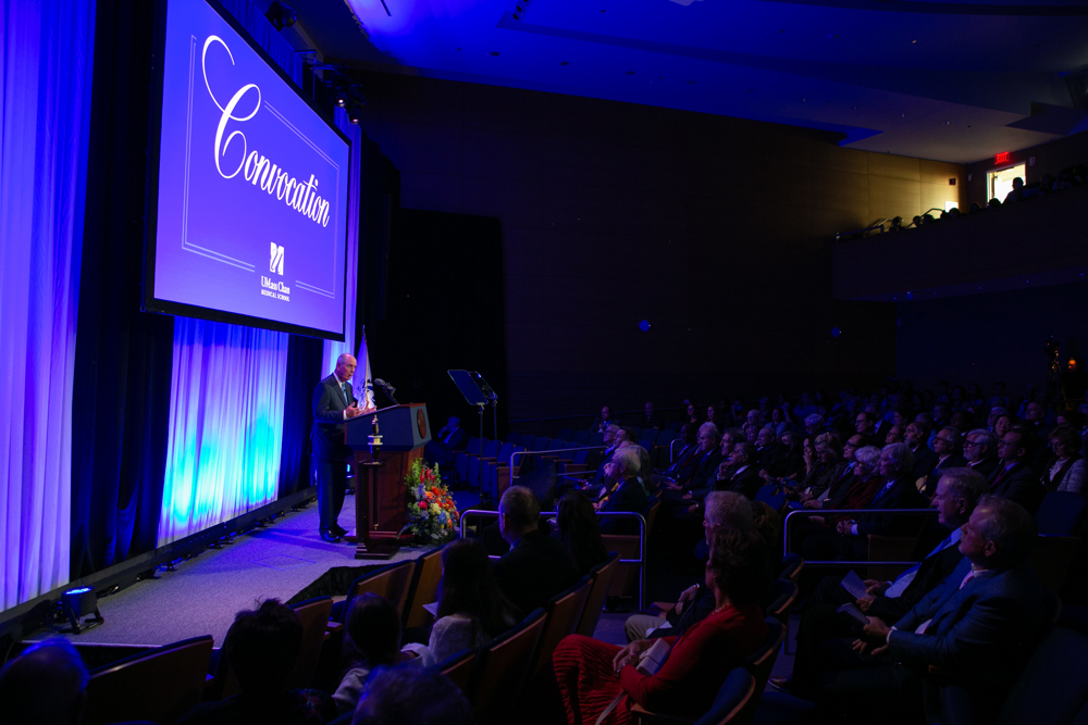  Photo of UMass Chan Chancellor Michael F. Collins addressing a crowd from a podium on a stage at the 2024 Convocation ceremony. 