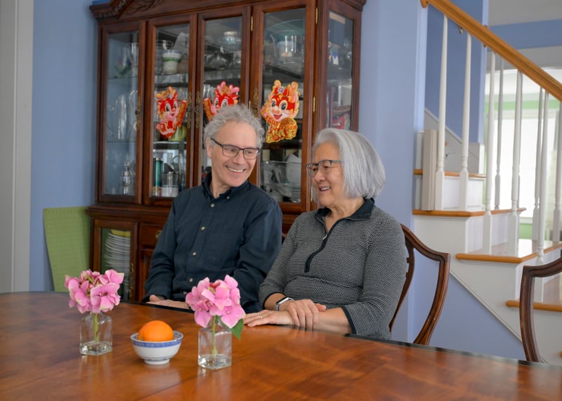Victor Ambros and Rosalind &ldquo;Candy&rdquo; Lee sit together at a table in their home