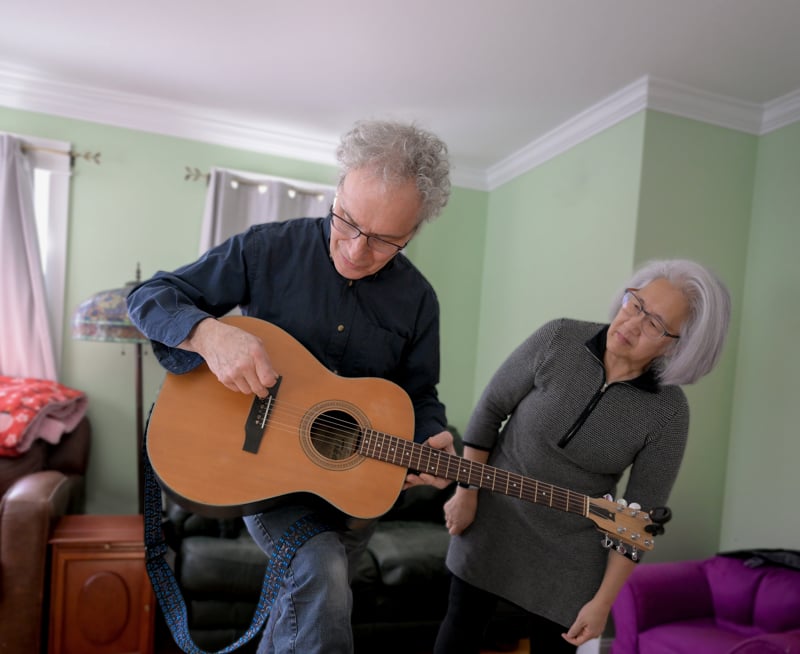 Lee watches as Ambros holds a guitar he rebuilt 