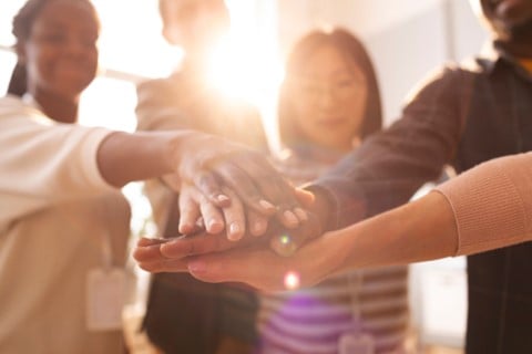 Support group of members with hands together in the middle of a circle