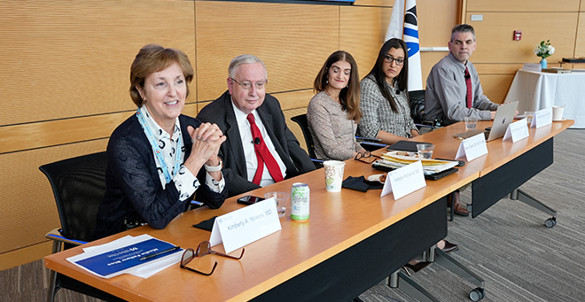 A panel of speakers sitting at a long table