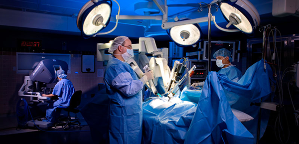 Image of an operating room with surgeons wearing operating gowns, masks, and gloves. 
