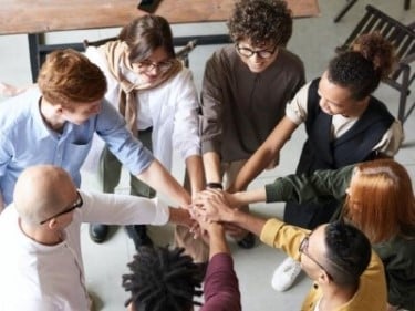 Group of diverse people in a circle with hand outstretched together