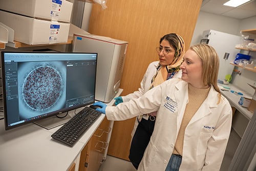 Photo of two researchers wearing white lab coats in a UMass Chan lab