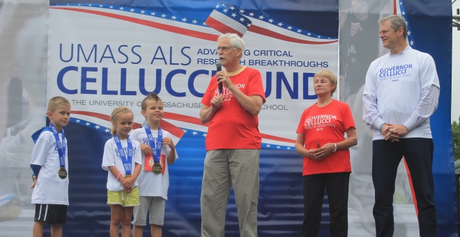 Internationally known ALS researcher Robert H. Brown Jr., DPhil, MD, talks to the crowd assembled at the 2nd Annual Governor Cellucci Tribute Road Race, as Jan Cellucci, Gov. Charlie Baker, and Cellucci’s grandchildren, Gabriel, Francesca and Rhys look on.