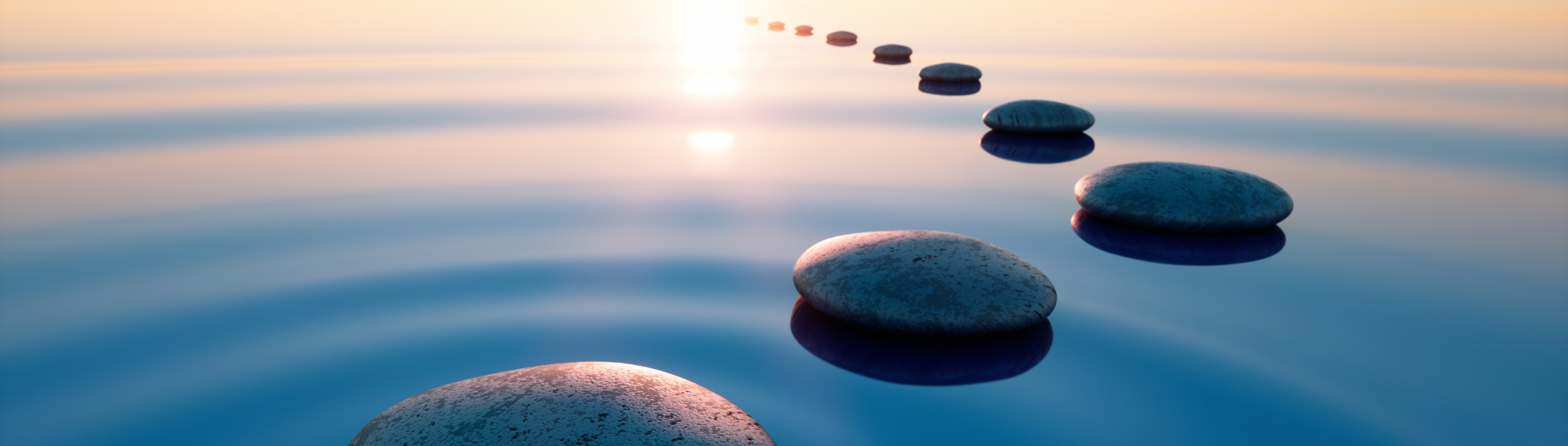 smooth stones arrange in an arc stretching off in a distance, floating on water, towards the setting sun